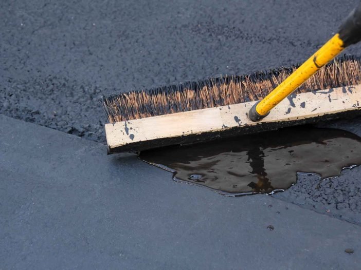 Crack sealant being spread over asphalt before the rainy season