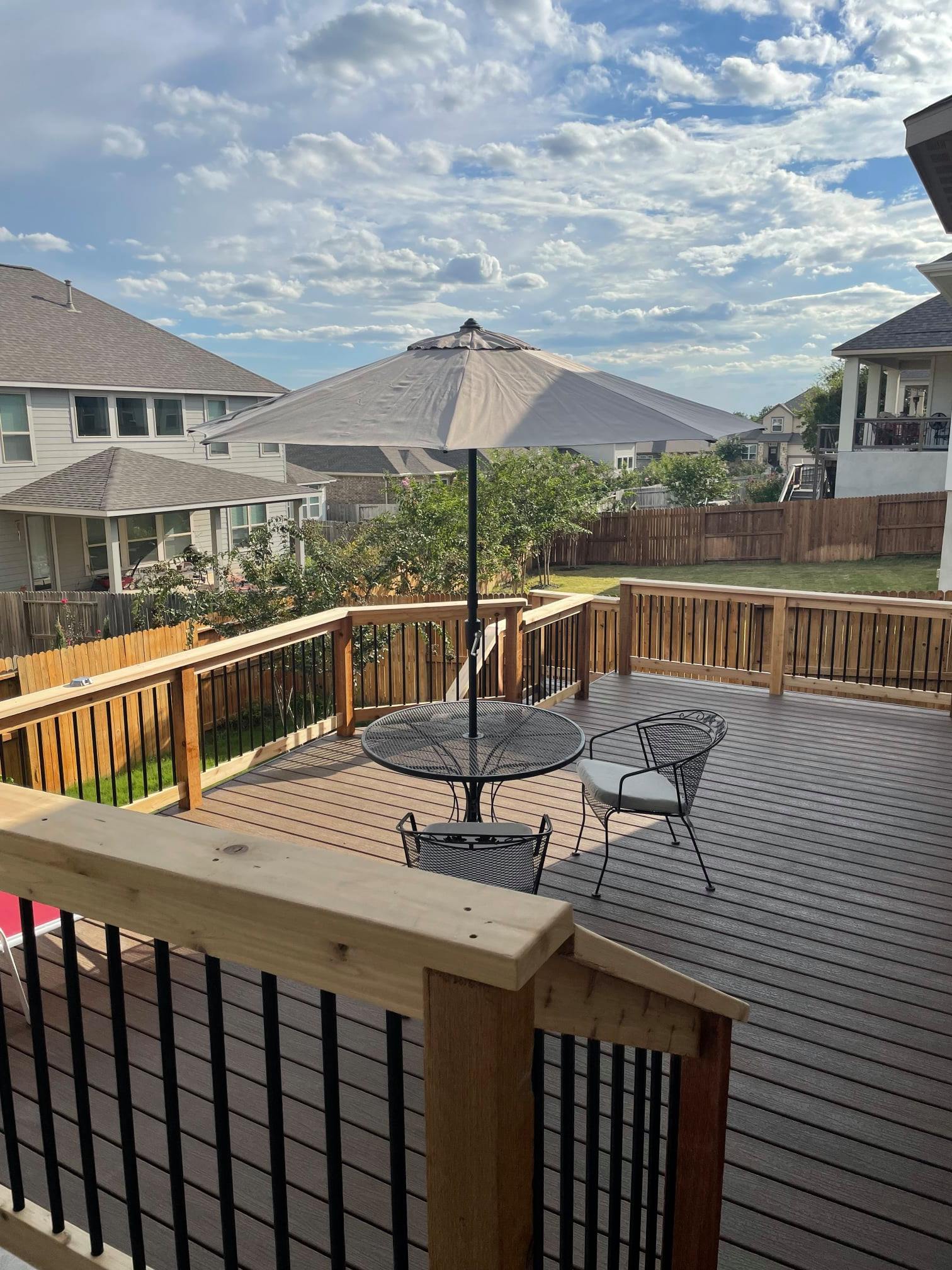 Composite deck with patio table and chairs and a railing with black metal balusters