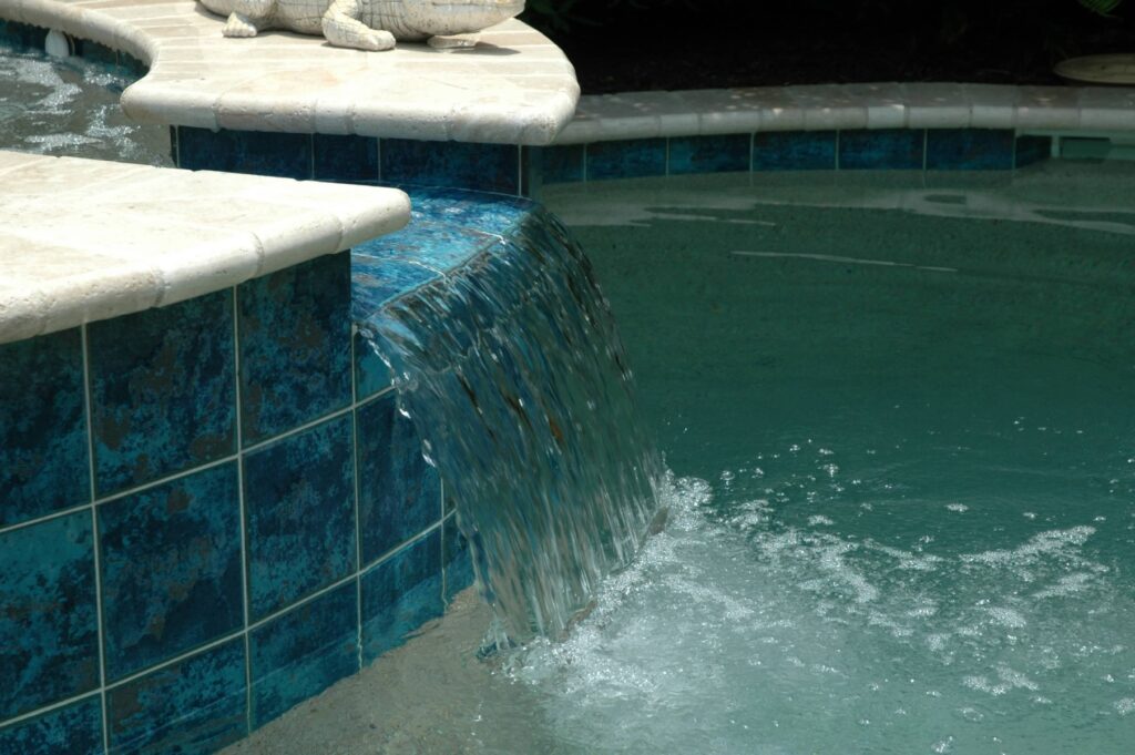 Close-up of a spa spillover with blue glass tile and a fresh pool interior finish