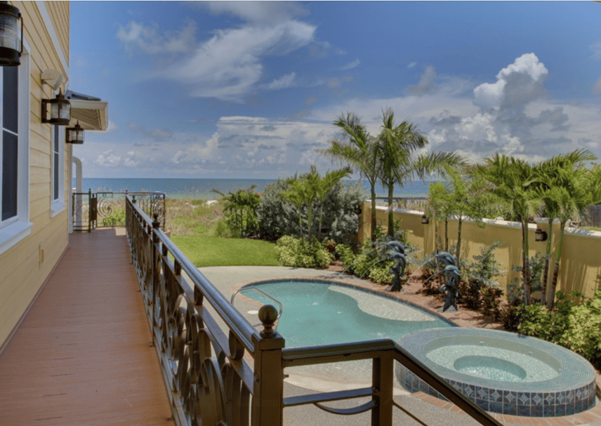 Beachfront pool and spa with wooden walkway and railing, Gulf of Mexico in the background