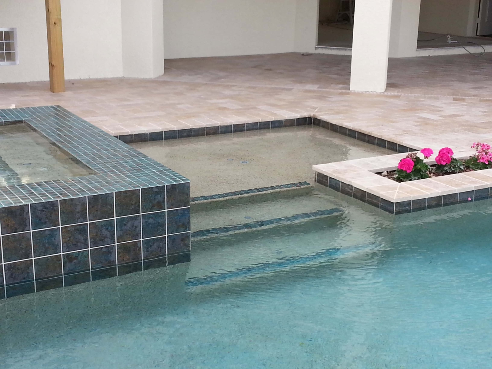 Pool steps and raised spa with blue tile and a light interior finish under a covered lanai